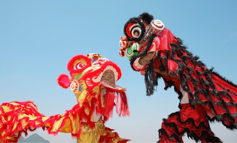 Two performers wearing brightly coloured dragon costumes for Global Gathering