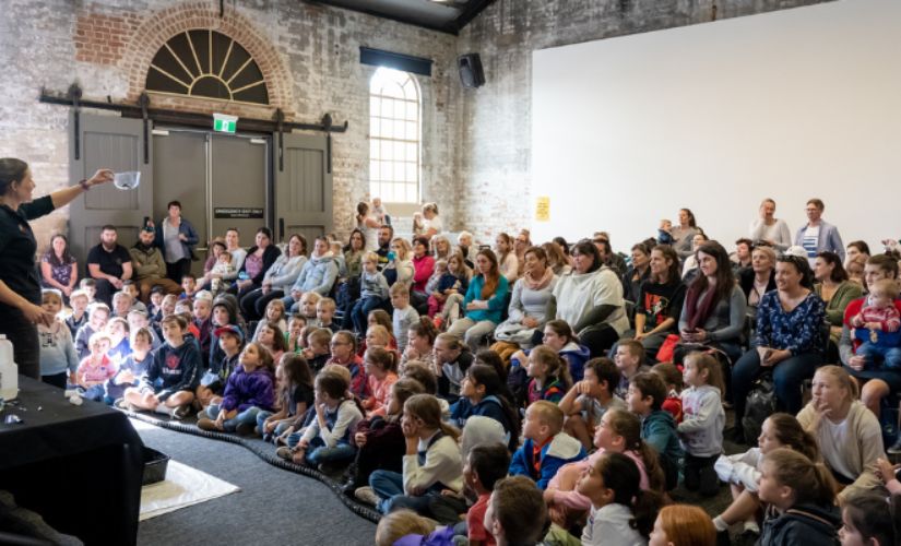 Scientist Catherine performing a science show in front of a crowd at the Museum